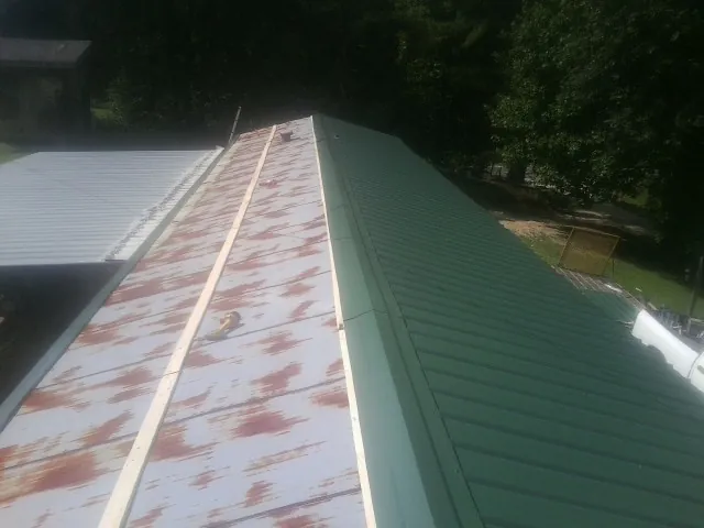 Old rusted panels beside newly installed green metal roofing — Wind Damage Roof Repair by Roofing Brothers in Fleetville