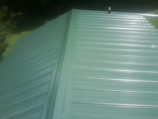 New green metal panels meeting at the ridge of a roof — Flat Roof Repair work by our crew in Fleetville