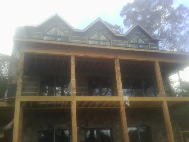 Dormers and porch framing on a large log home under construction — Roof Coating work by our crew in Fleetville