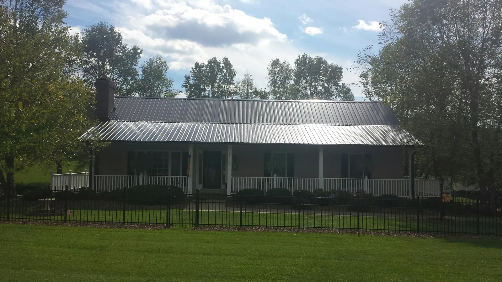 Gray metal roof on a brick ranch with a full width front porch — Gutter Guard Installation work by our crew in Fleetville