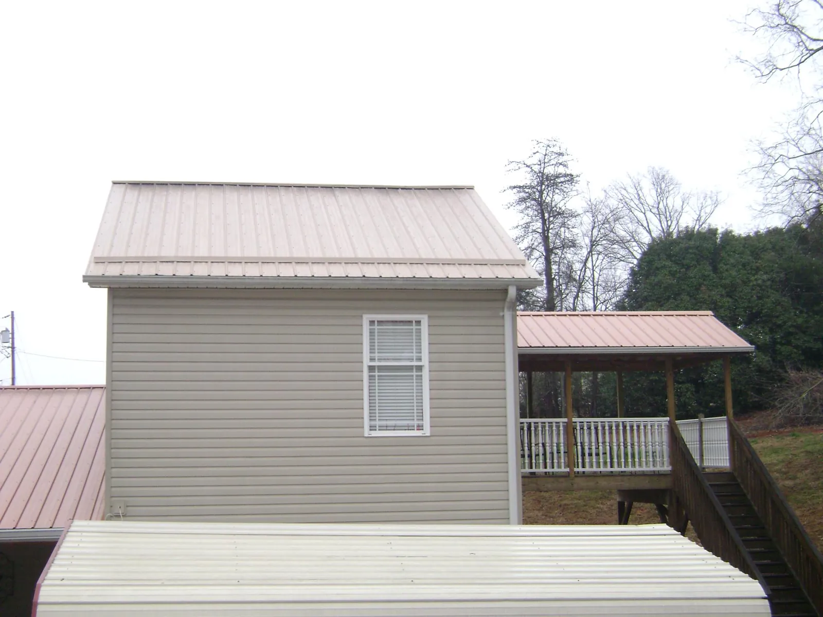 Tan metal roofs on a two story addition and attached porch, from a Roof Replacement job in Fleetville