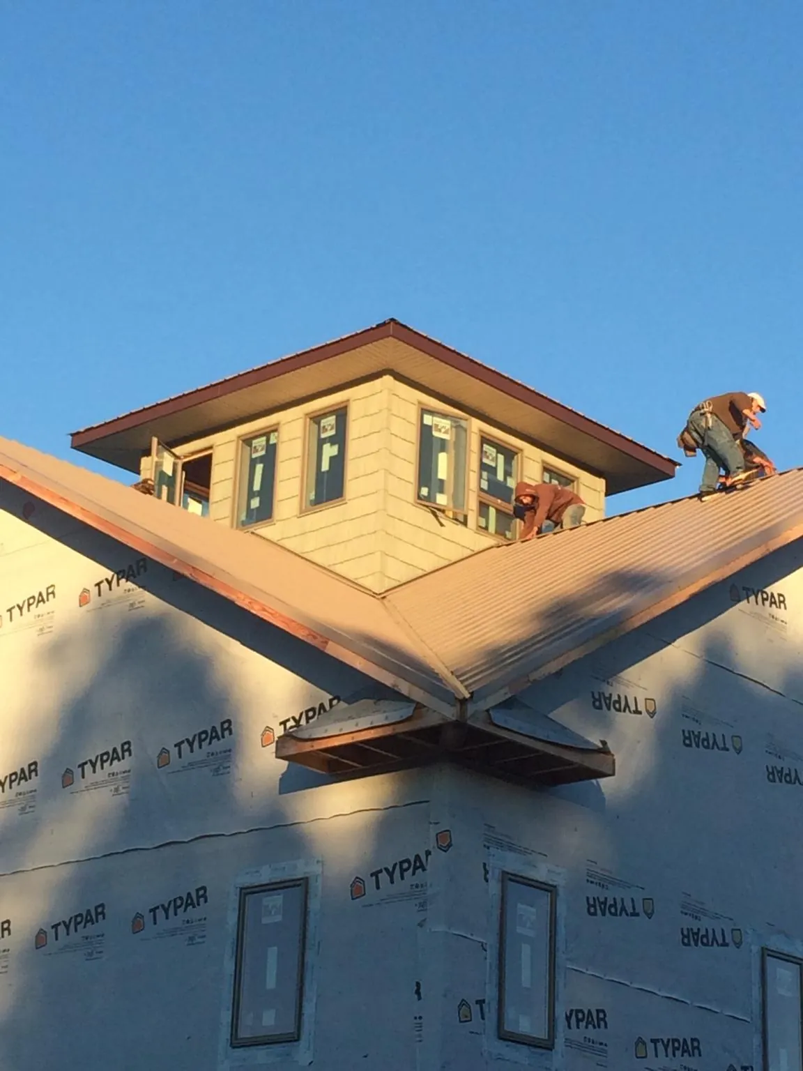 Roofers working around a rooftop cupola on a new metal roof at sunset — Roof Waterproofing in Fleetville by Roofing Brothers